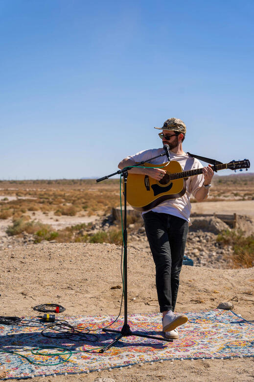 Charles McDonald singing and playing guitar on the banks of the Salton Sea.