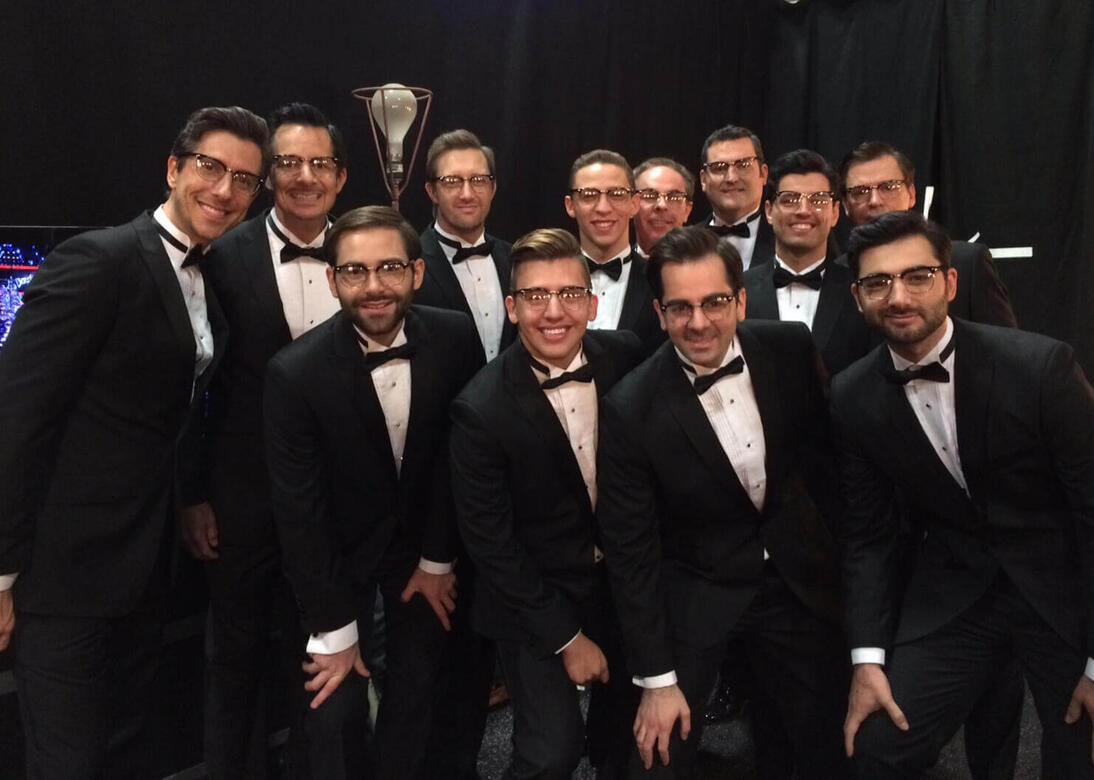 Charles McDonald with a group photo of background singers wearing tuxedos and glasses on The Voice